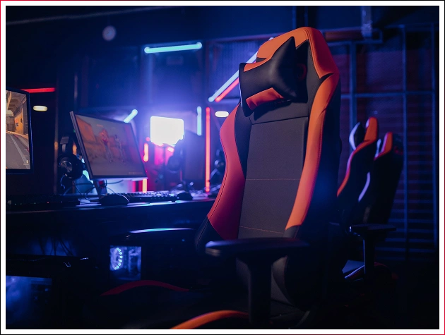 Detailní záběr herního křesla na pozadí svítících monitorů v herním klubu.